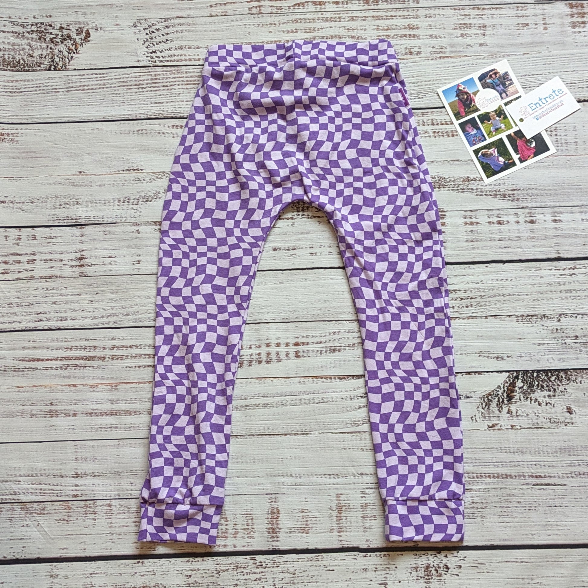 The fab purple trippy checked harem joggers. Handmade from soft and stretchy cotton jersey, with an elasticated waist and roll-able ankle cuffs. Shown from the rear.