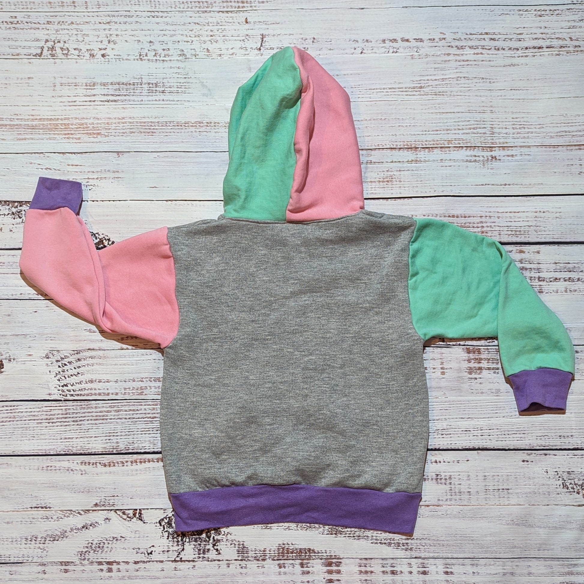 Rear view of the purple trippy checked hoodie.. Handmade in purple trippy checked cotton jersey, pink, mint and grey cotton French terry and purple cotton ribbing. A fun mix of patterns and colours that you can rock together.