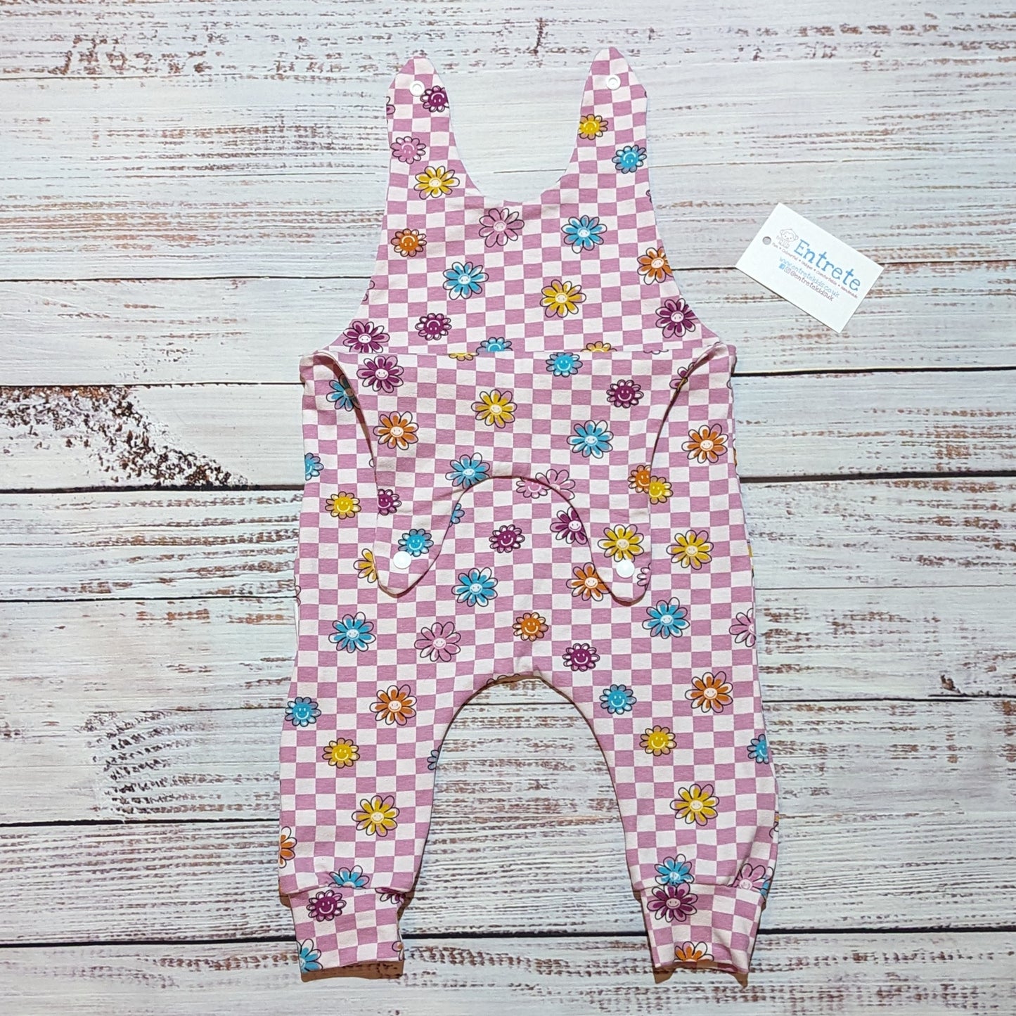 Pink checked happy flowers sleeveless romper. With shoulder popper entry and roll-able ankle cuffs. Handmade in soft and comfy cotton jersey. Shown with shoulder popper entry open.