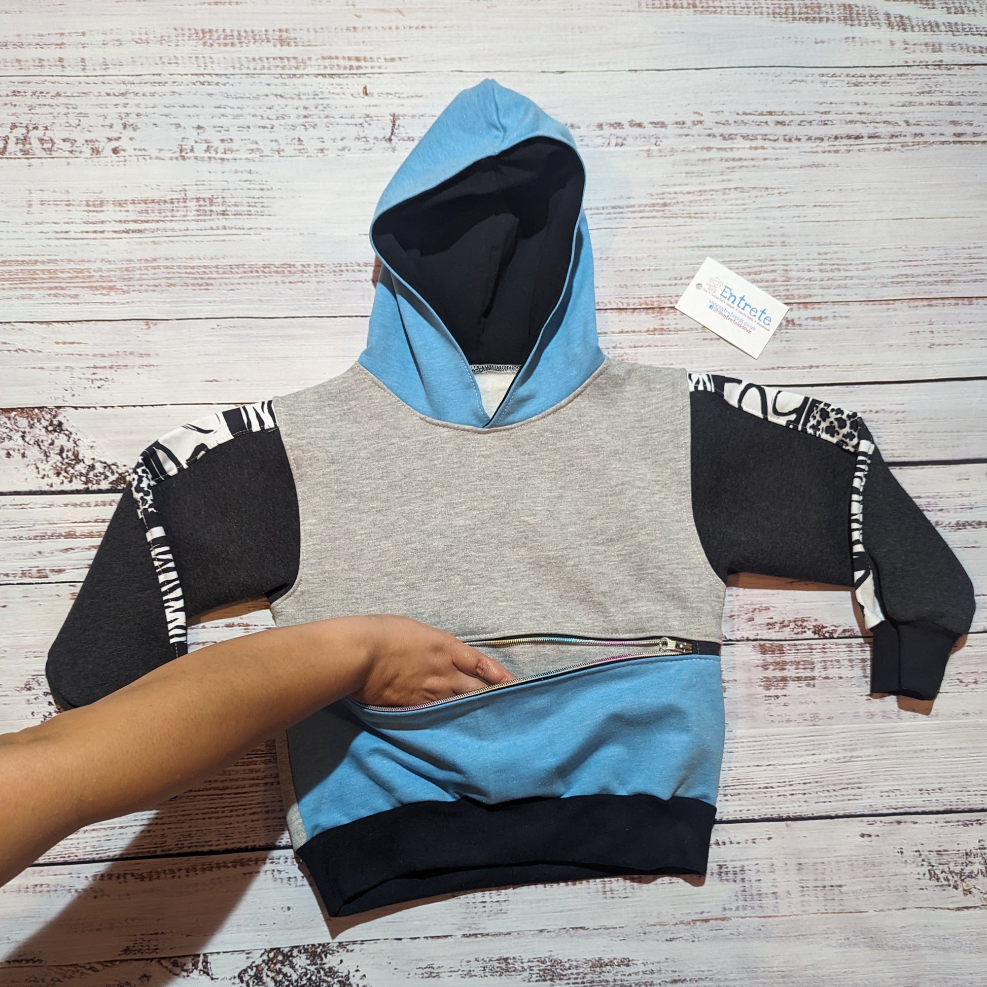 The sky blue animal hearts hoodie. Demonstrating the zipped front pocket.