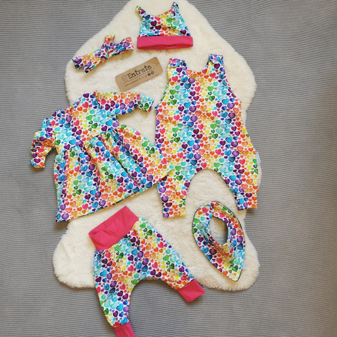 The full gift set, including dress, romper, harem pants, bib and tie top hat. Shown in rainbow hearts for demonstration purposes. Your gift set will be made using monochrome abstract stripes cotton jersey.