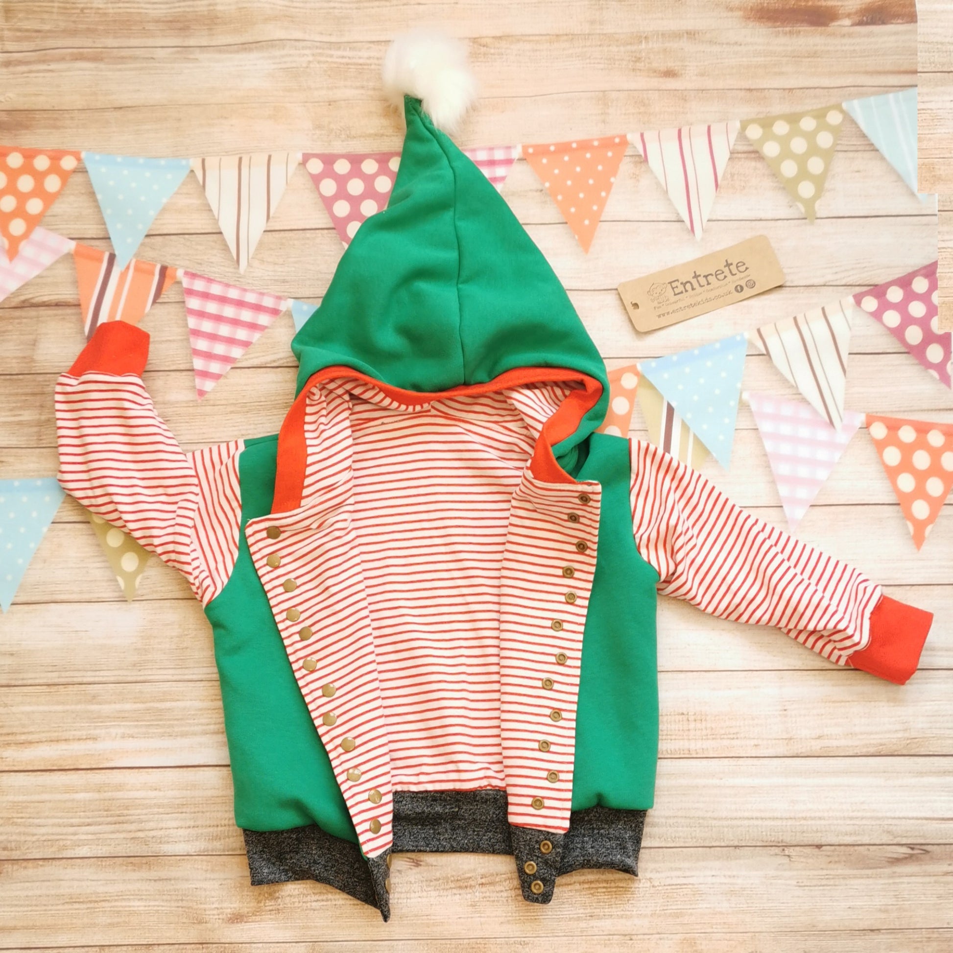 Fantastically fun reversible elf hoodie. Handmade in green cotton sweatshirt fleece, with red striped cotton jersey arms, graphite ribbing waist and red ribbing cuffs . With adorable pom-pom hood. Shown open, revealing red striped reverse.