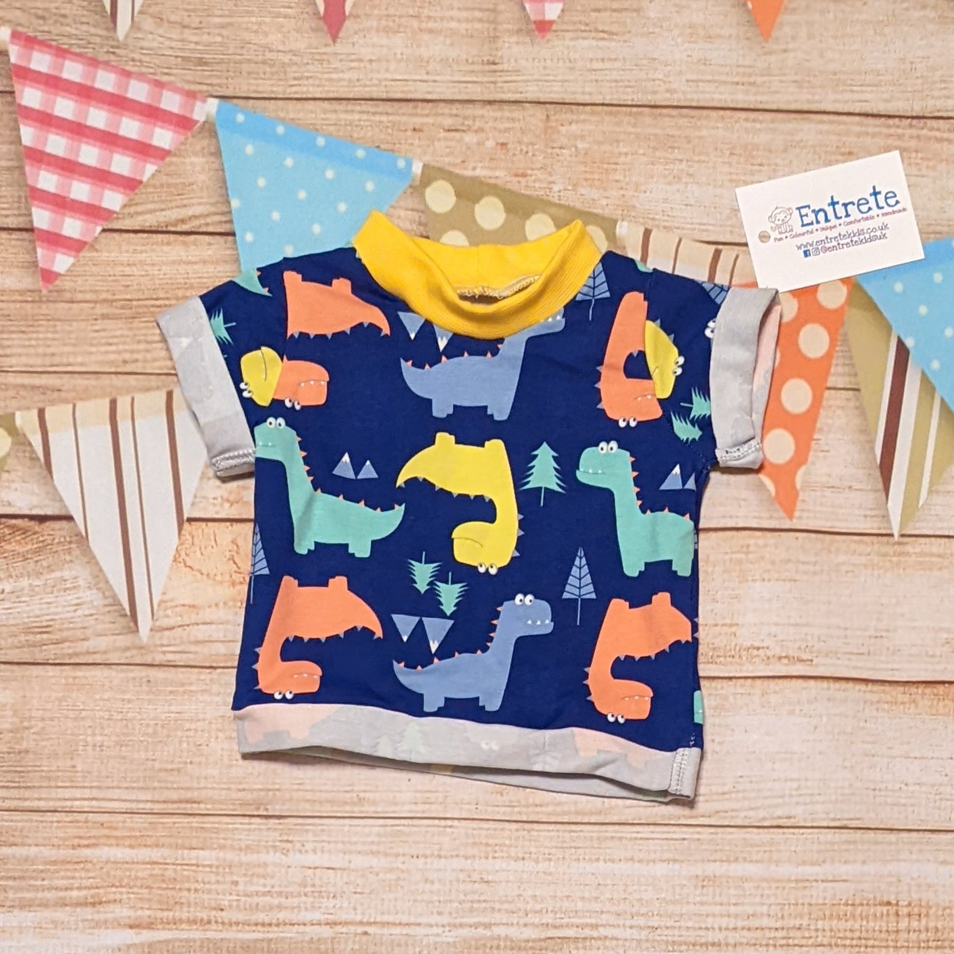 Colourful and fun blue dinosaurs short sleeved T-Shirt. Handmade using blue dinosaurs cotton jersey and yellow cotton ribbing.