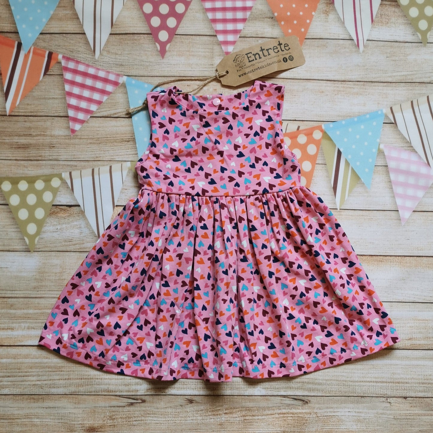 Front of Girls & Babies sleeveless back popper dress, handmade using pretty pink mini hearts cotton jersey.