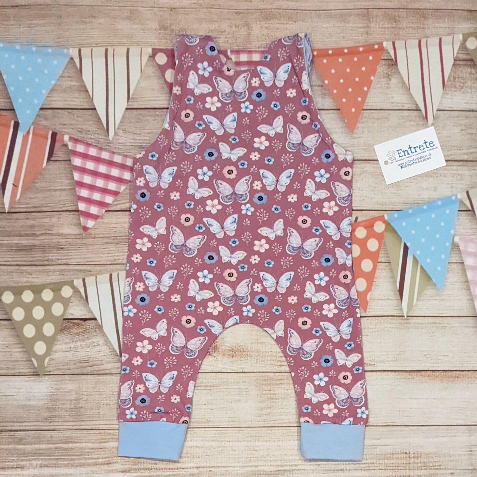 Pretty pink butterflies on contrasting sky blue sleeveless romper. Handmade using organic pink butterflies cotton jersey and sky blue cotton jersey. Shown from the rear.