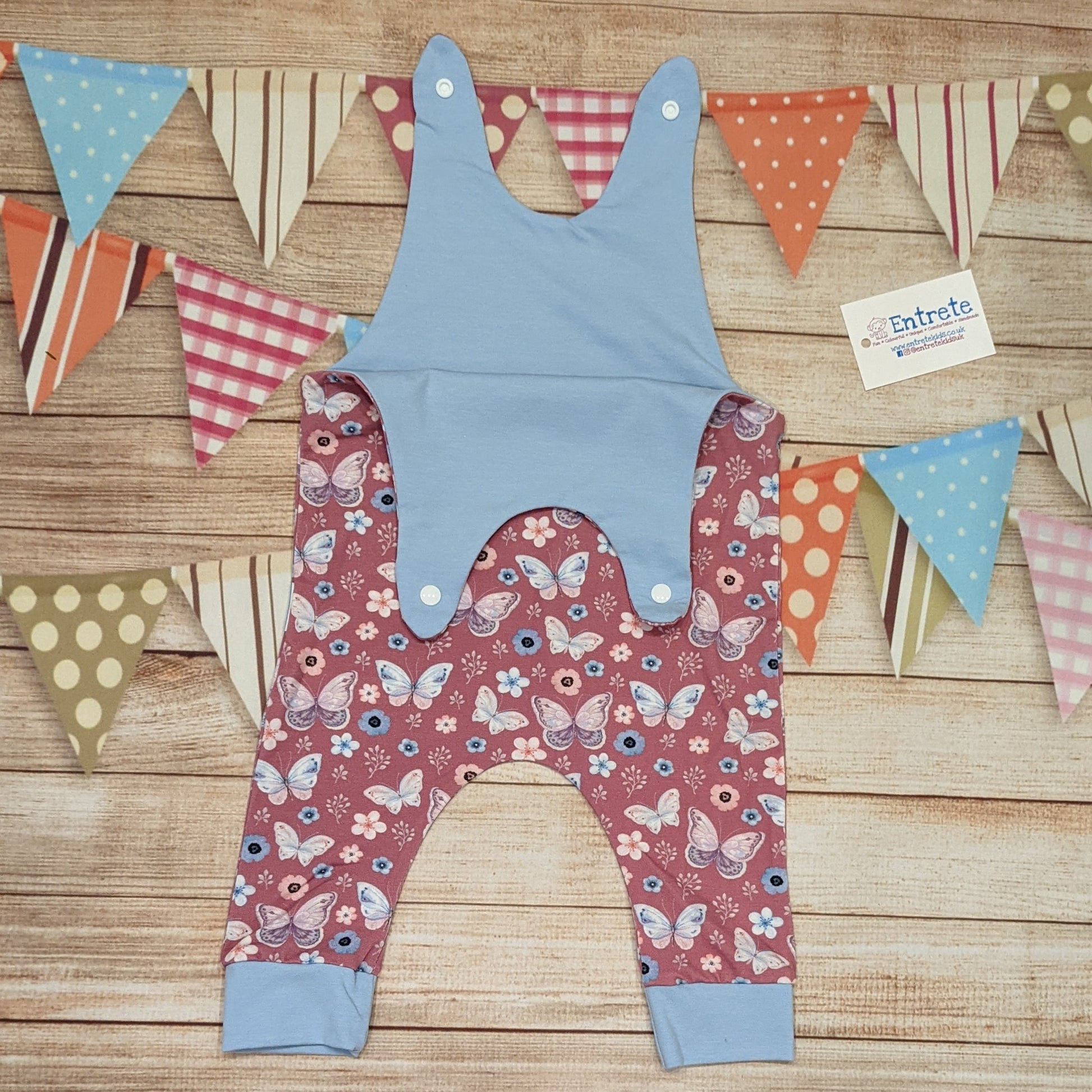 Pretty pink butterflies on contrasting sky blue sleeveless romper. Handmade using organic pink butterflies cotton jersey and sky blue cotton jersey. Shown with shoulder popper entry open.