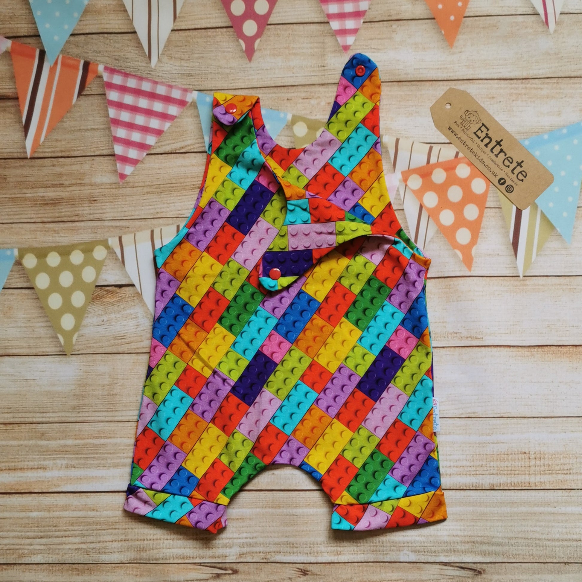 Unisex Kids sleeveless romper shorts, handmade using colourful building blocks cotton jersey. Perfect for Lego lovers. Shown with one of the shoulder poppers open.