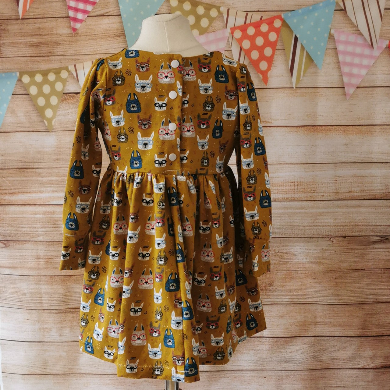 Adorably fun girls and babies back popper dress. Handmade using soft and comfy mustard bunny faces cotton jersey. Shown with long sleeves, from the rear with poopers down to the waist as on sizes 9-12 months and above.