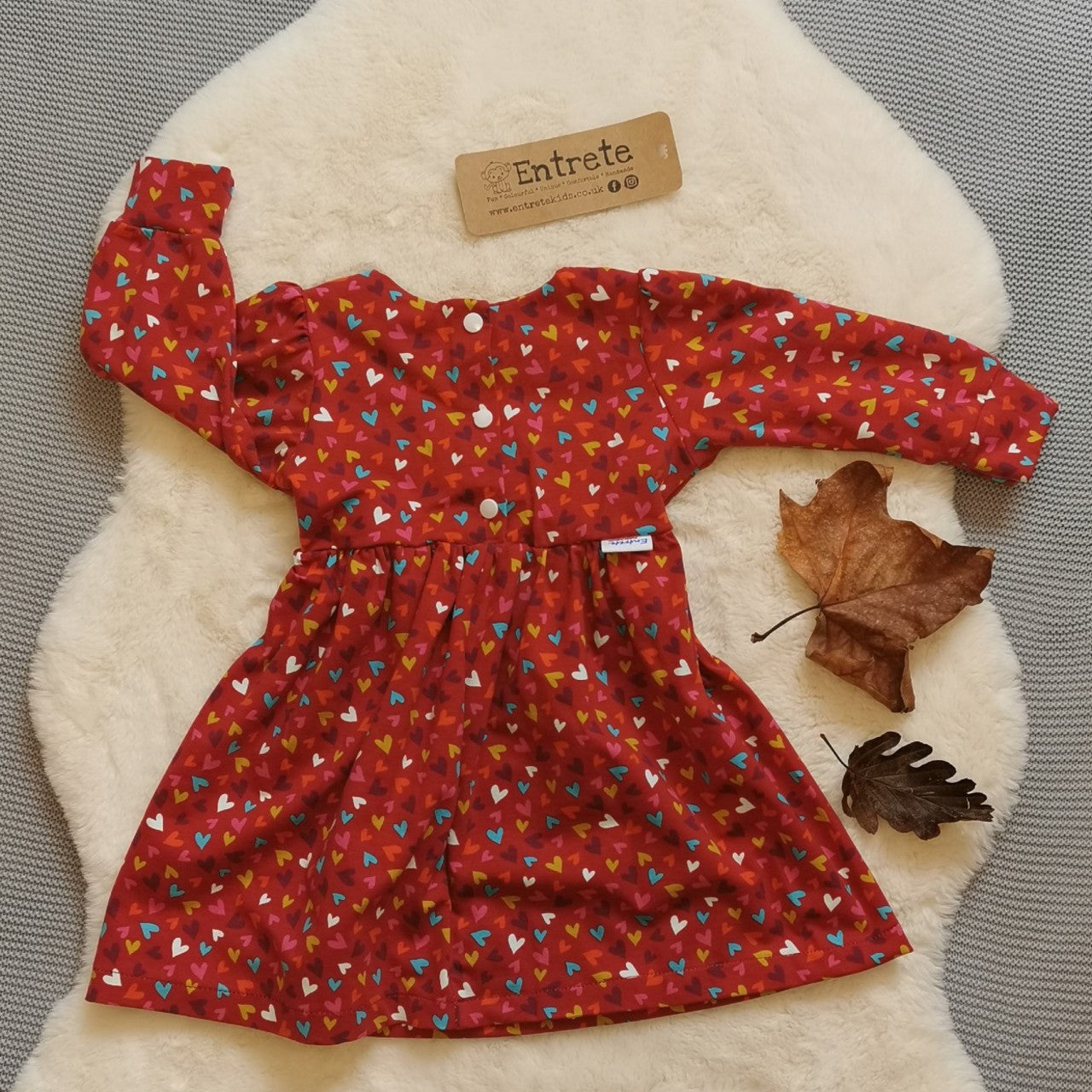 Rear view of the autumnal red min hearts dress. Lovingly handmade from soft and comfortable red mini hearts cotton jersey. Version shown is with poppers to the waist as seen on sizes 9-12 Months and over.